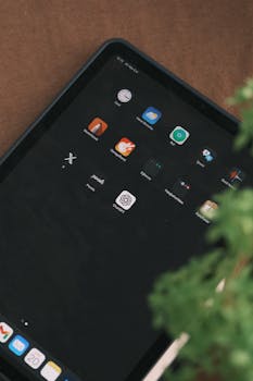 Tablet screen with app icons and green plant, emphasizing technology and nature balance.
